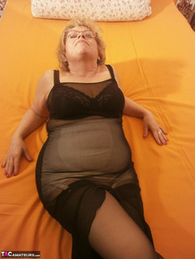 Tipsy hot granny Caro spreading legs on the bed wearing black stockings