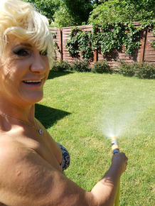 Mature blonde woman takes off her bikini while wandering around her property