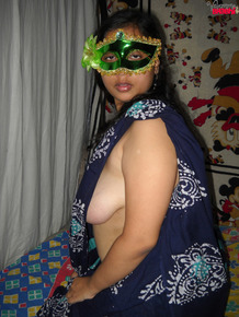 Fat Indian woman Juicy covers up her naked tits after getting naked in a mask