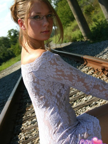 Amateur solo girl poss non nude on train tracks in tight dress and glasses