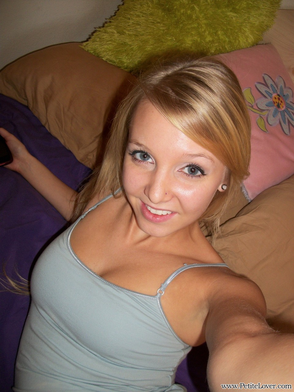 Cute teen girl with blonde hair displays her hairless pussy on her photo