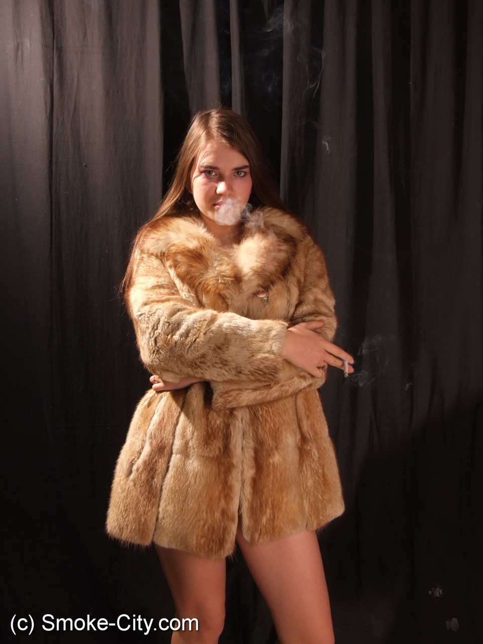 Amateur model smokes while removing fur coat for nude poses