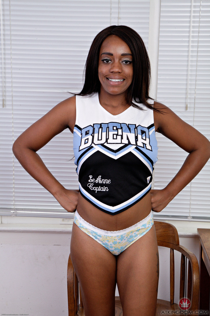 Black amateur removes her cheerleader uniform to model in the nude image