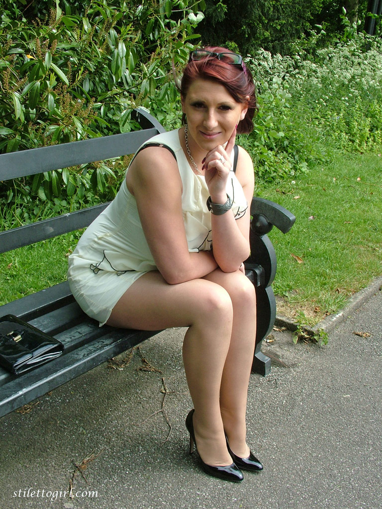Thick woman in glasses shows off her stiletto heels on a park bench photo pic