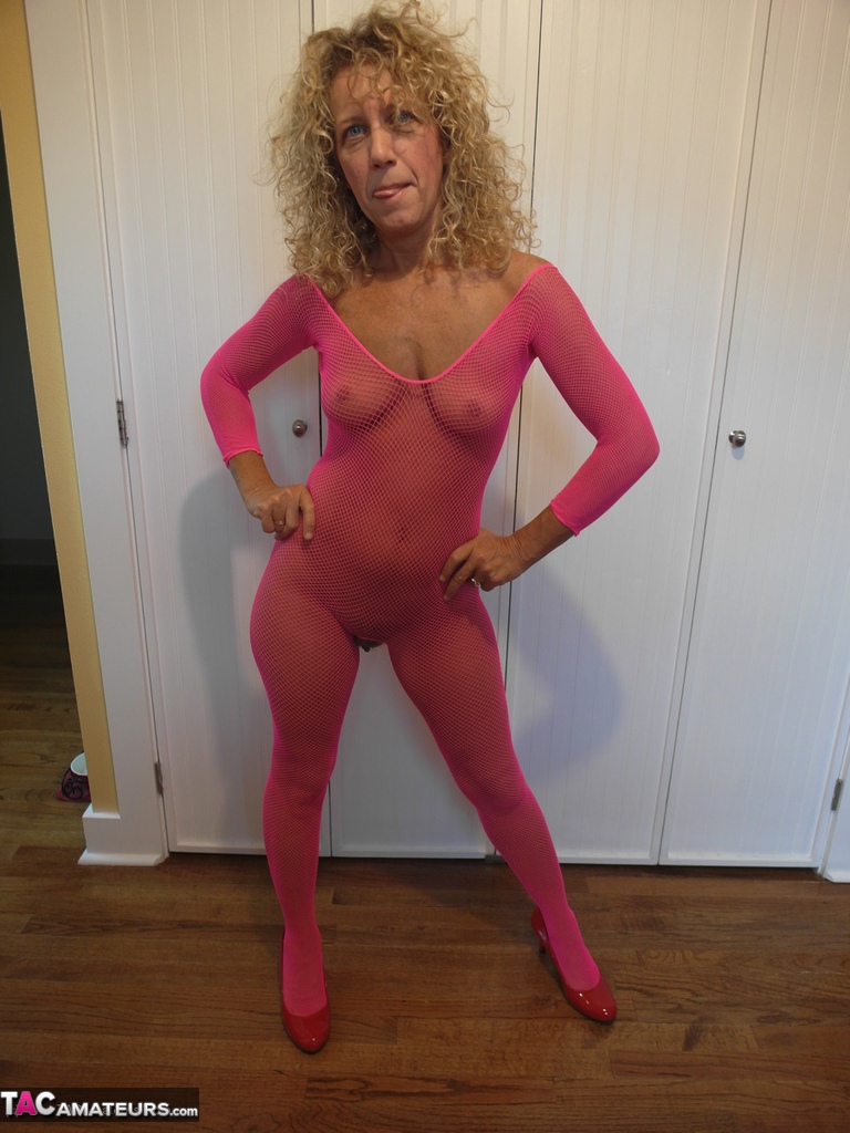Mature lady with curly blonde hair frees her boobs from pink bodystocking